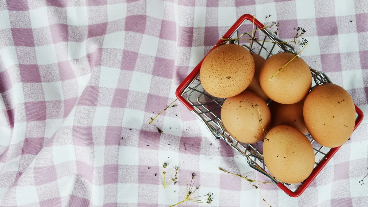 Brown eggs in a small wire basket on a checked cloth