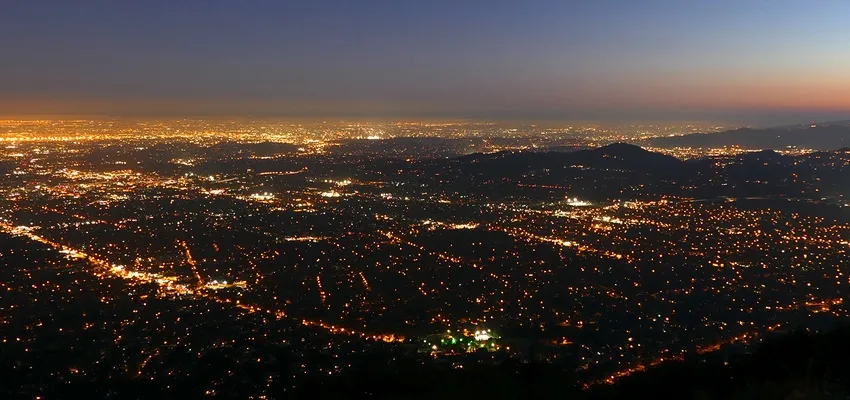 City lights at night seen from above, stretching across a hilly metropolitan area