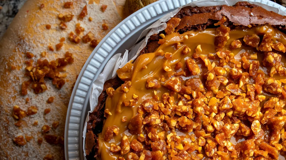 Caramel and chopped nut topped pie on a round tray