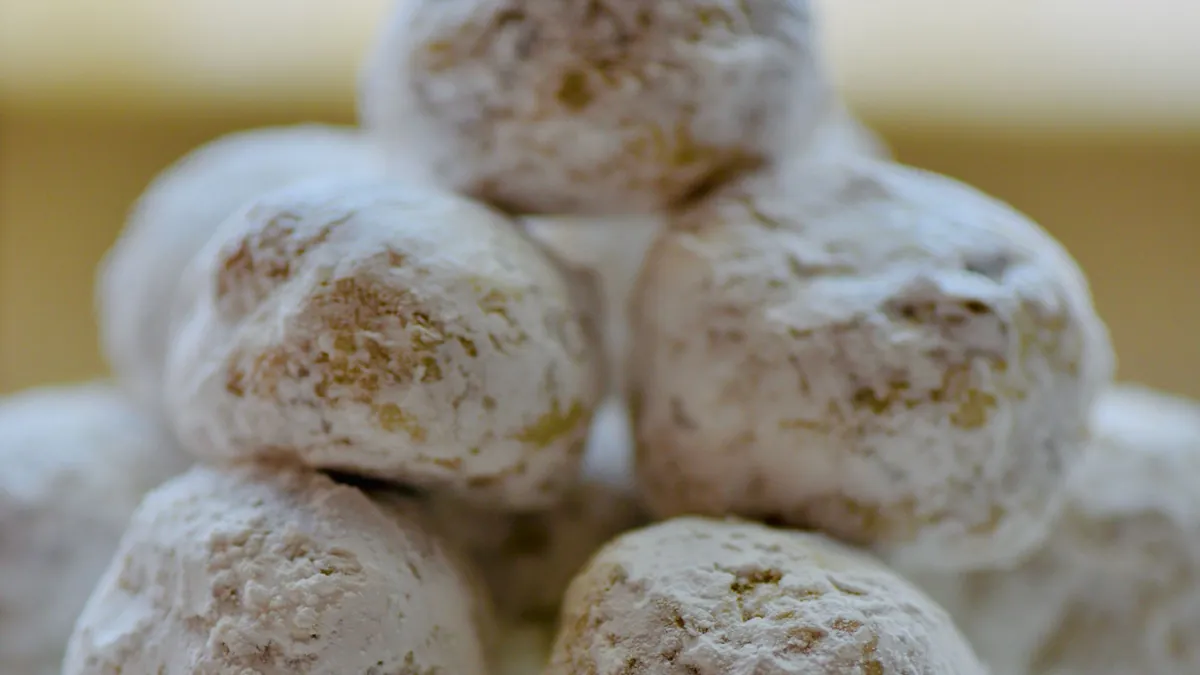 Powdered sugar cookies piled on a glass cake stand