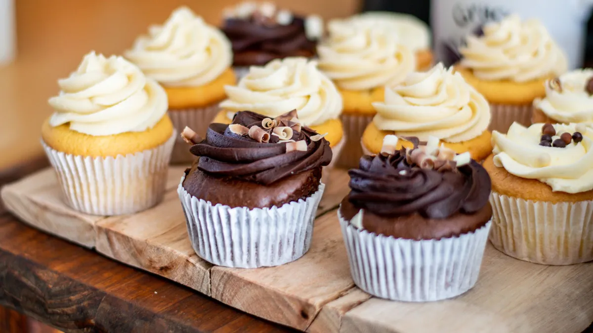 Chocolate and vanilla cupcakes with swirled frosting on a wooden board
