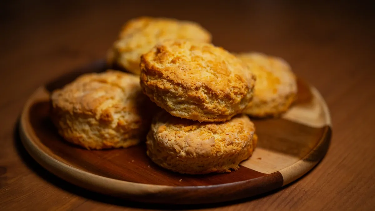 Golden homemade biscuits stacked on a wooden plate