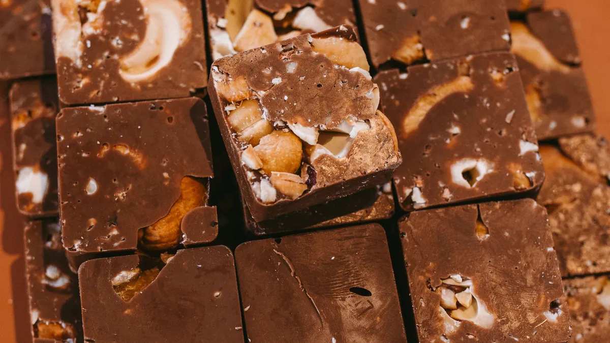 Squares of chocolate nut fudge stacked on a terracotta plate