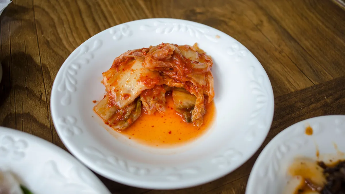 Kimchi on a white plate on a wooden table
