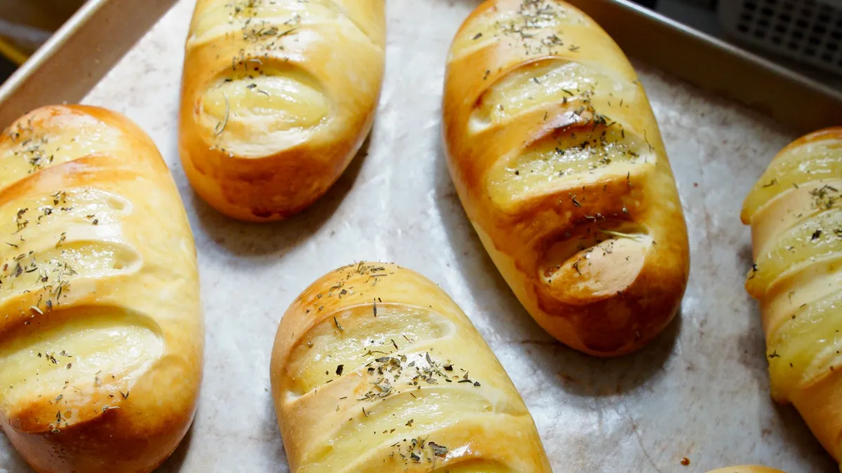 Golden potato bread rolls on a baking tray