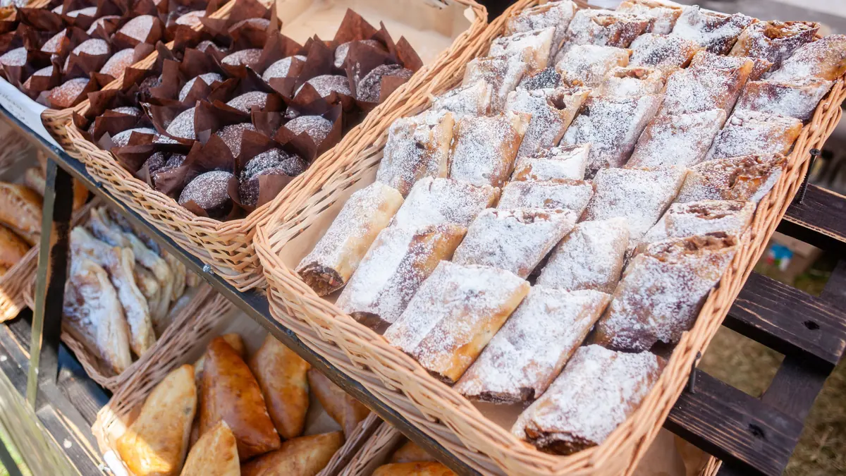 Baskets of chocolate muffins and powdered-sugar pastries on a market stall