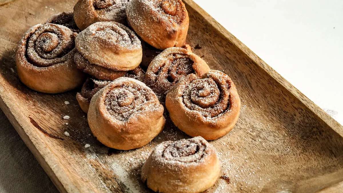 Cinnamon rolls dusted with sugar on a wooden tray