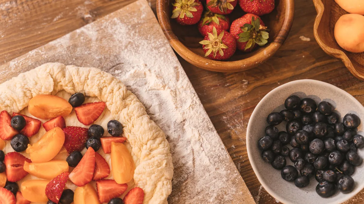 Rustic fruit tart with strawberries, apricots and blueberries on a floured board