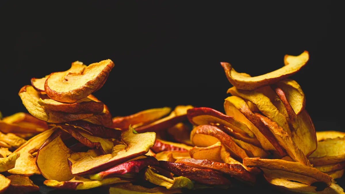 Dried apple slices piled on a dark surface