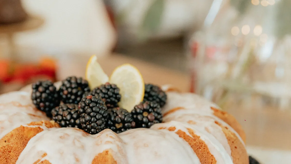 Bundt cake with white icing topped with blackberries and lemon slices