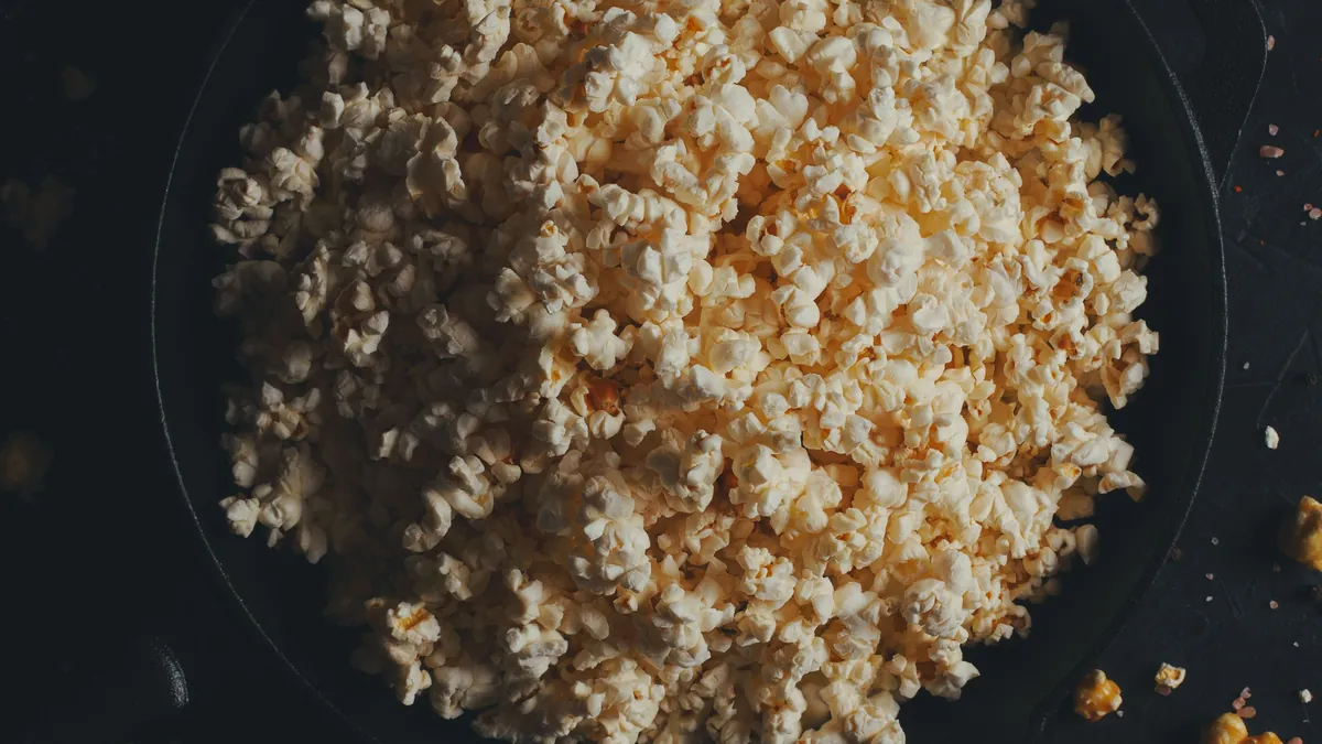 Bowl of popcorn on a dark table with smaller bowls of snacks