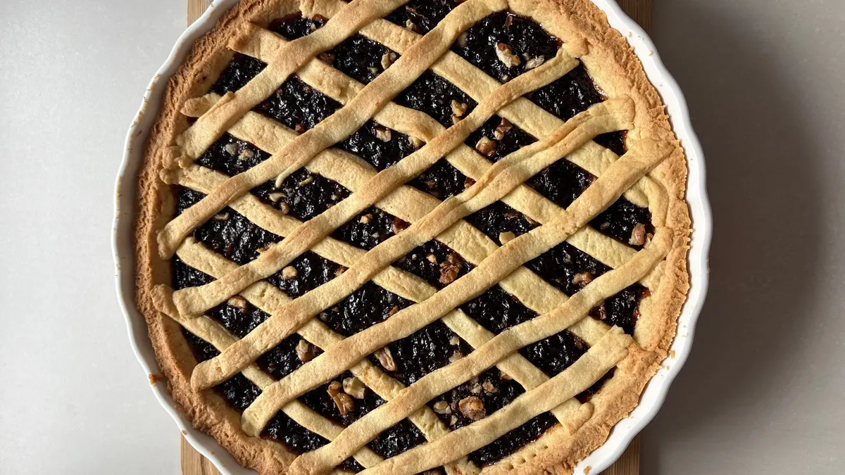 Lattice-top fruit pie with nuts in a white baking dish