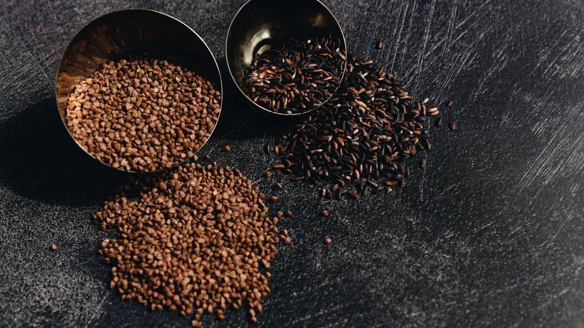 Dry grains in small metal bowls on a dark surface