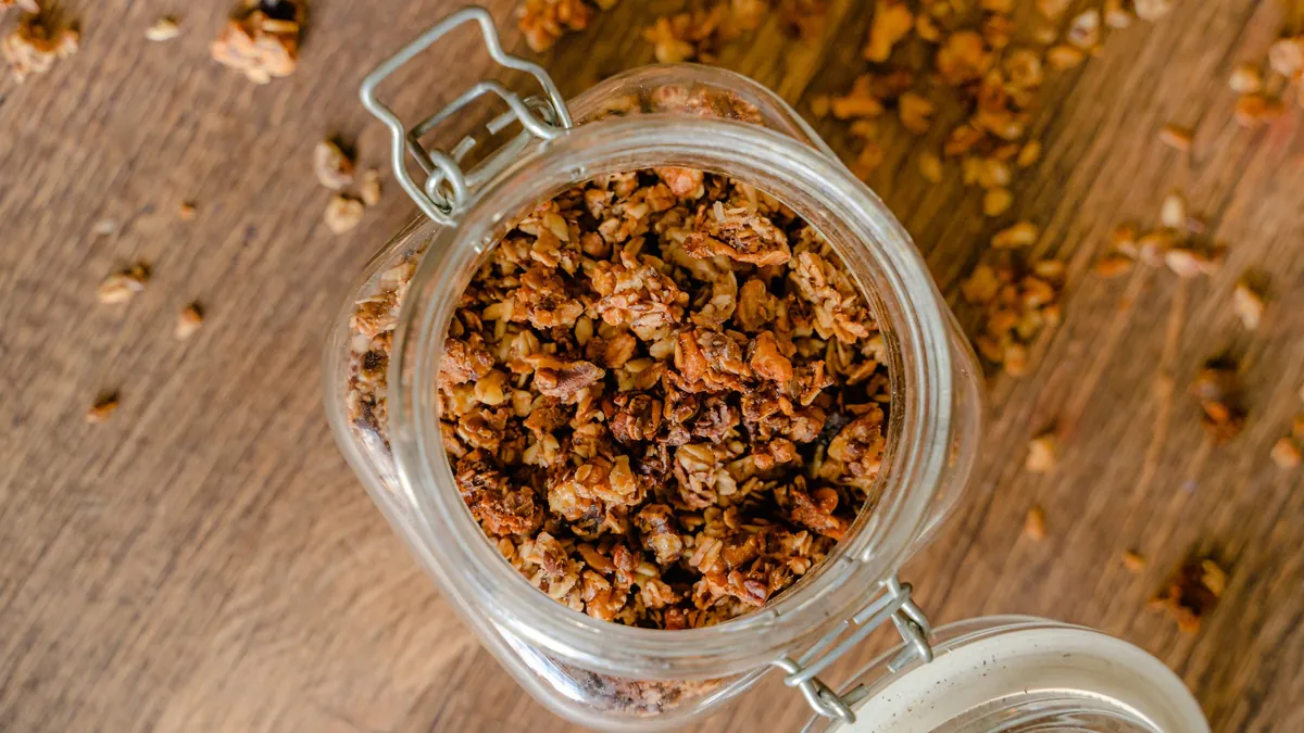Open glass jar of homemade granola on a wooden table