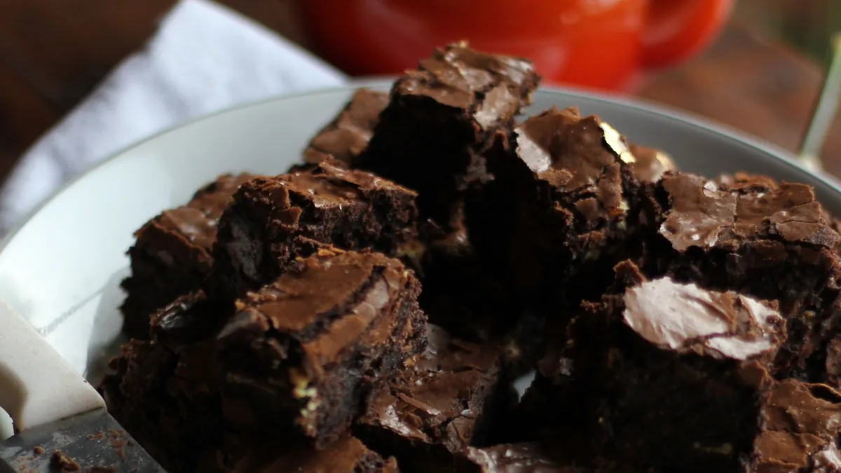Chocolate brownies stacked on a white plate