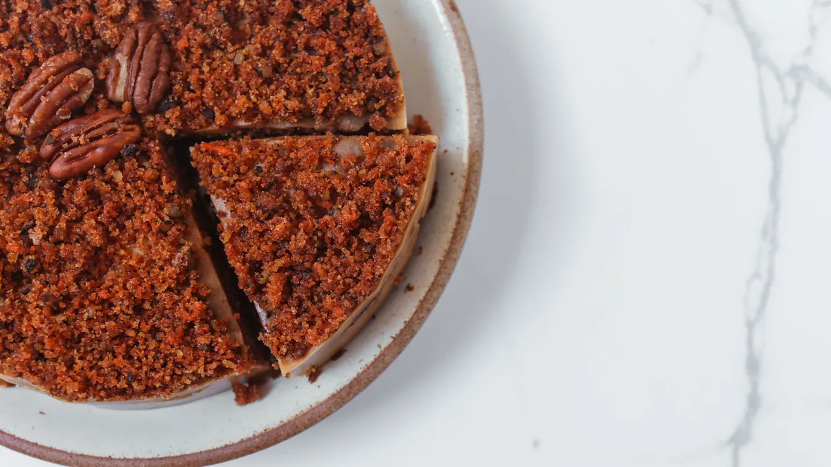 Crumb-topped pecan cake on a ceramic plate with a slice cut