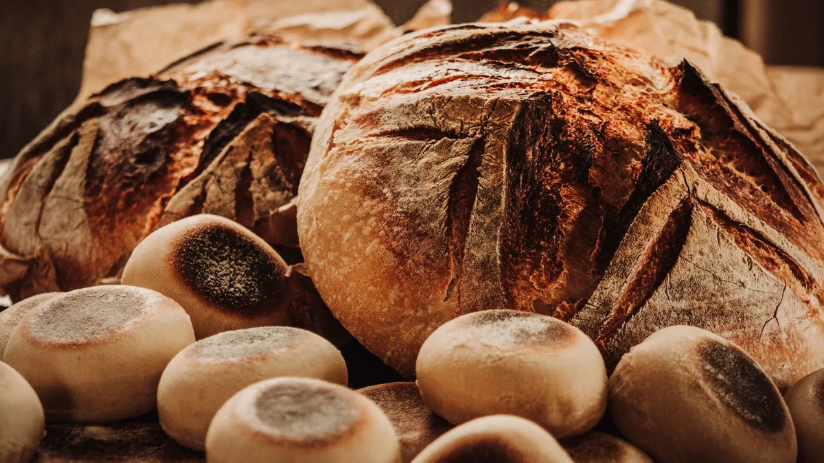 Rustic sourdough loaves and small round rolls on a wooden table