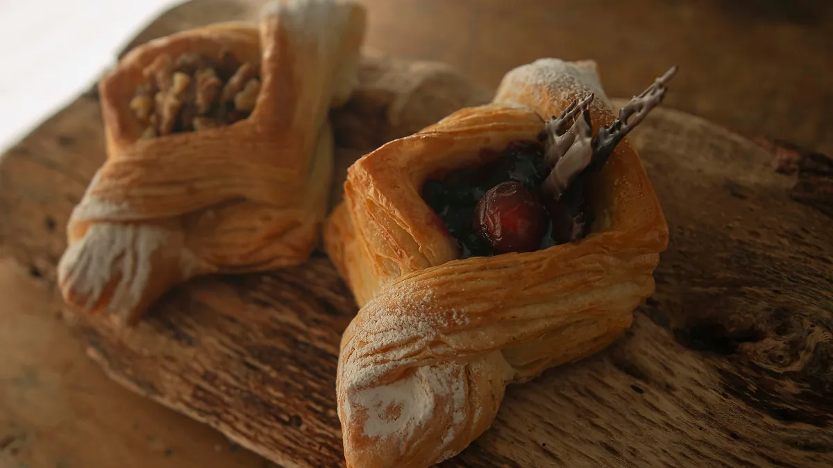 Two Danish pastries with fruit and nuts on a wooden board