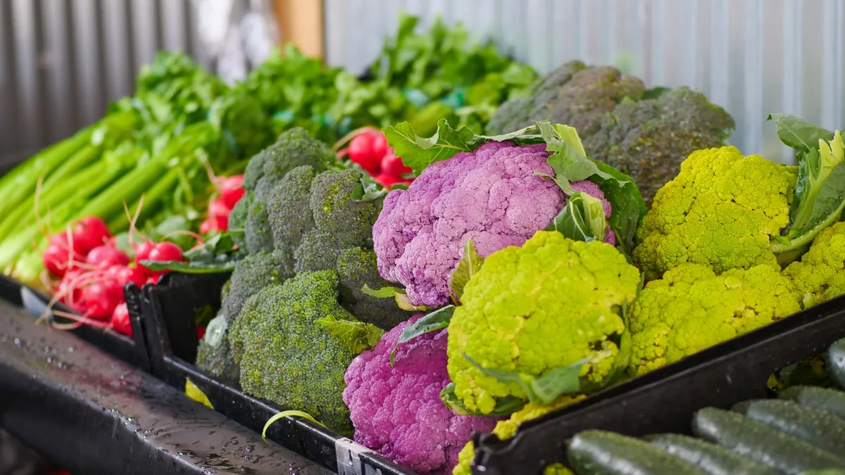 Crates of cauliflower, broccoli, radishes and cucumbers at a market stall