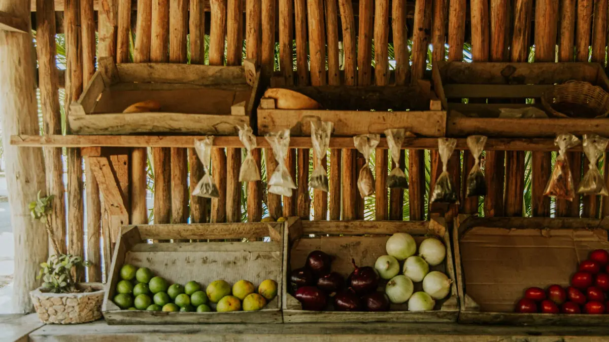 Wooden crates of limes, onions and tomatoes on a rustic wooden market stand