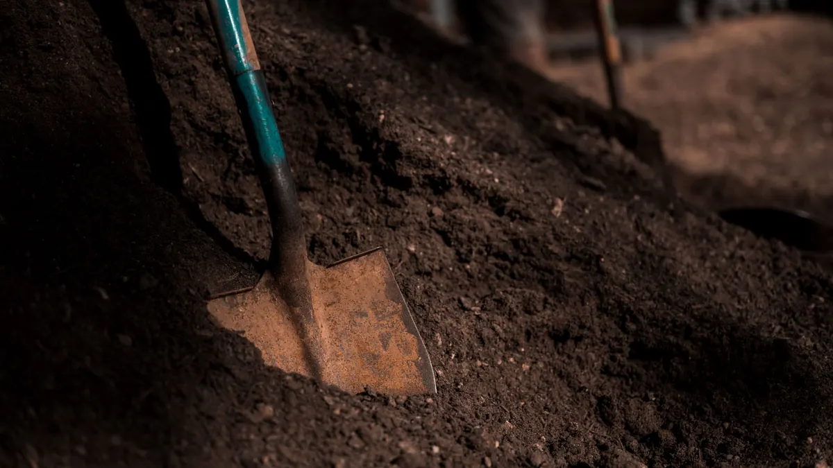 A shovel standing in a pile of dark garden soil